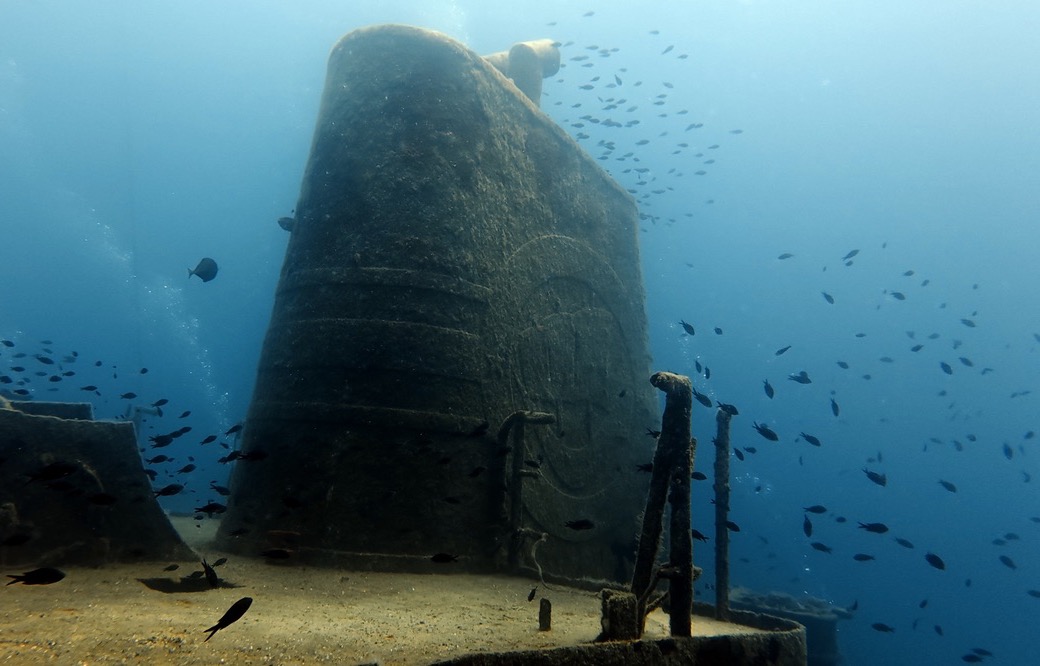 The funnel of the Um El Faroud wreck surrounded by a swarm of damselfish